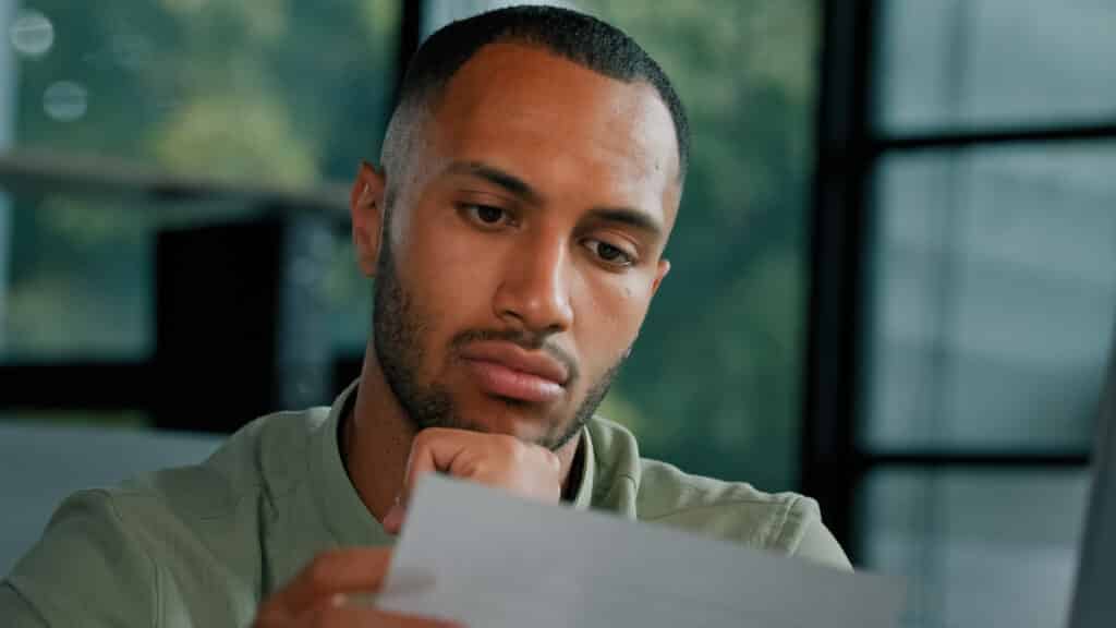 Man holding a paper, wondering about how visa or citizenship status affects his workers compensation rights