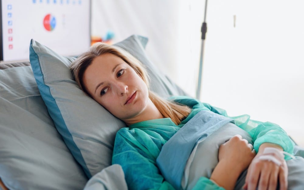 Woman lying in bed after experiencing birth trauma and medical negligence.